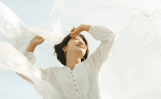 白い服を着て、透き通る布を広げる女性